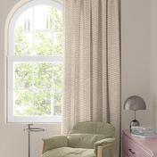 Okno s barevn&yacute;m květinov&yacute;m z&aacute;věsem v červen&eacute;, oranžov&eacute; a modr&eacute;, zelen&eacute; křeslo a mal&yacute; stolek s lampou